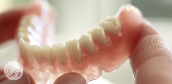  A person holding a dental implant alongside a natural tooth, showcasing dental restoration options.