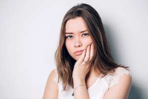 A woman covers her mouth with her hand, expressing surprise or contemplation.