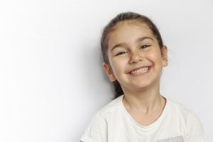 A smiling little girl sits happily on a chair, radiating joy and innocence
