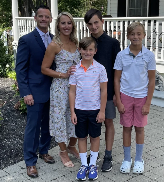 A family stands together for a photo in front of their home.