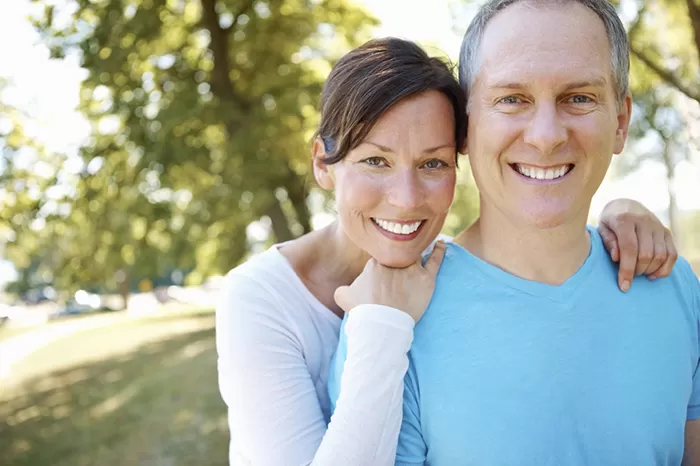 A happy middle-aged couple smiling outdoors.