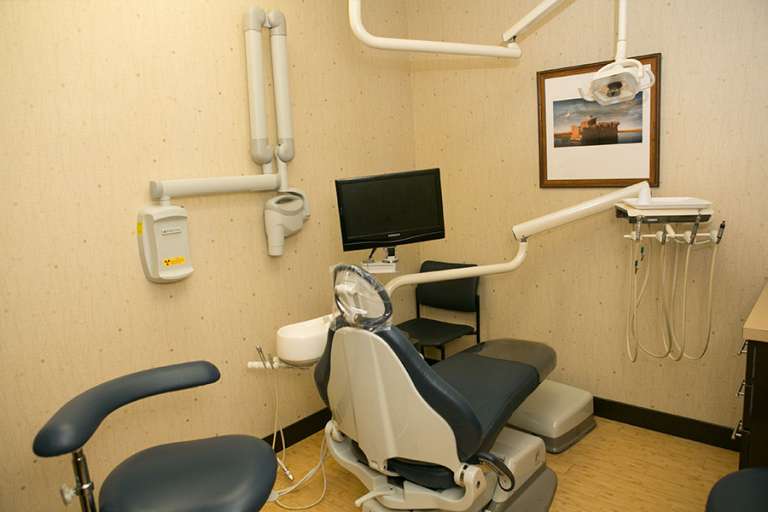 A dental office featuring a chair and various dental equipment for patient care and treatment.