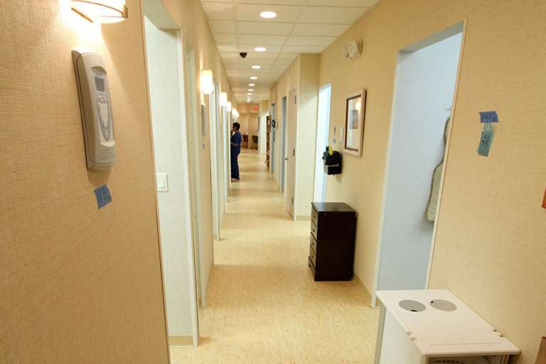 A well-lit hallway in a dental clinic with multiple exam room doors and a clean, professional atmosphere