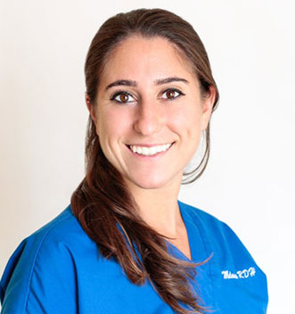 Smiling female healthcare professional in blue scrubs against a plain white background.