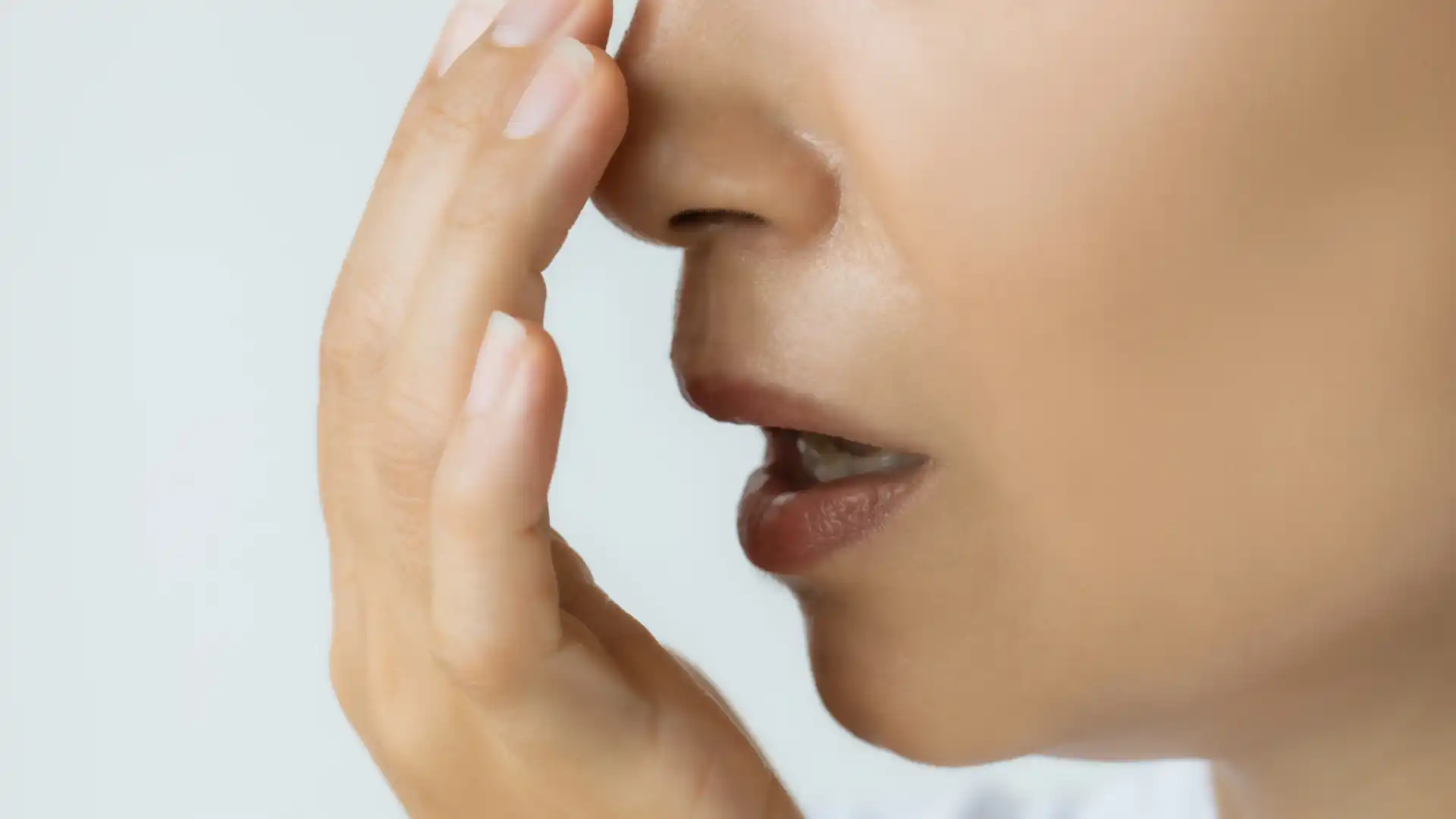 Woman checking for bad breath by breathing into her hand