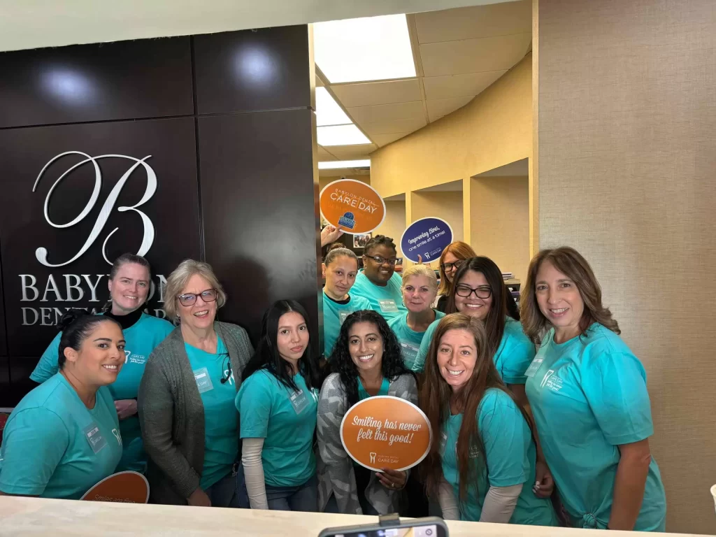 A baby boy smiling with a dental team, showcasing a joyful moment in a dental care setting.