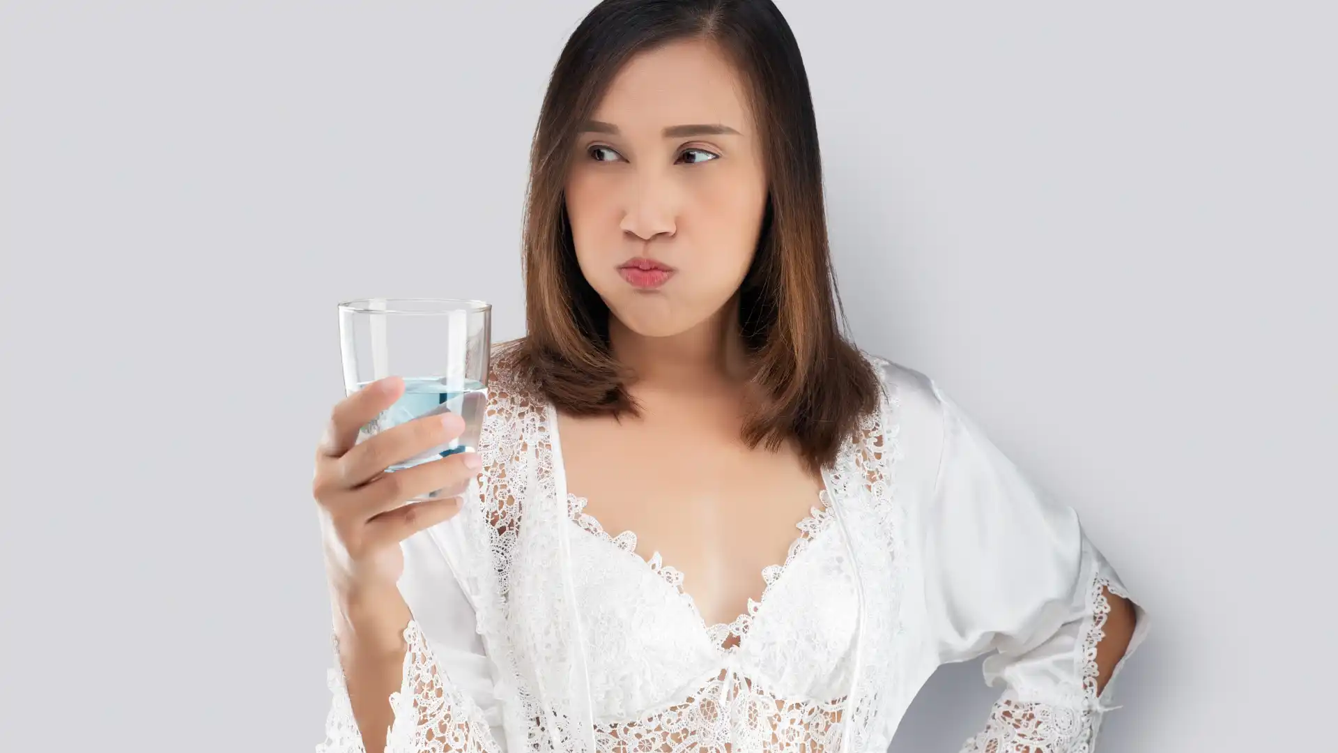 Woman rinsing her mouth with blue mouthwash while holding a glass