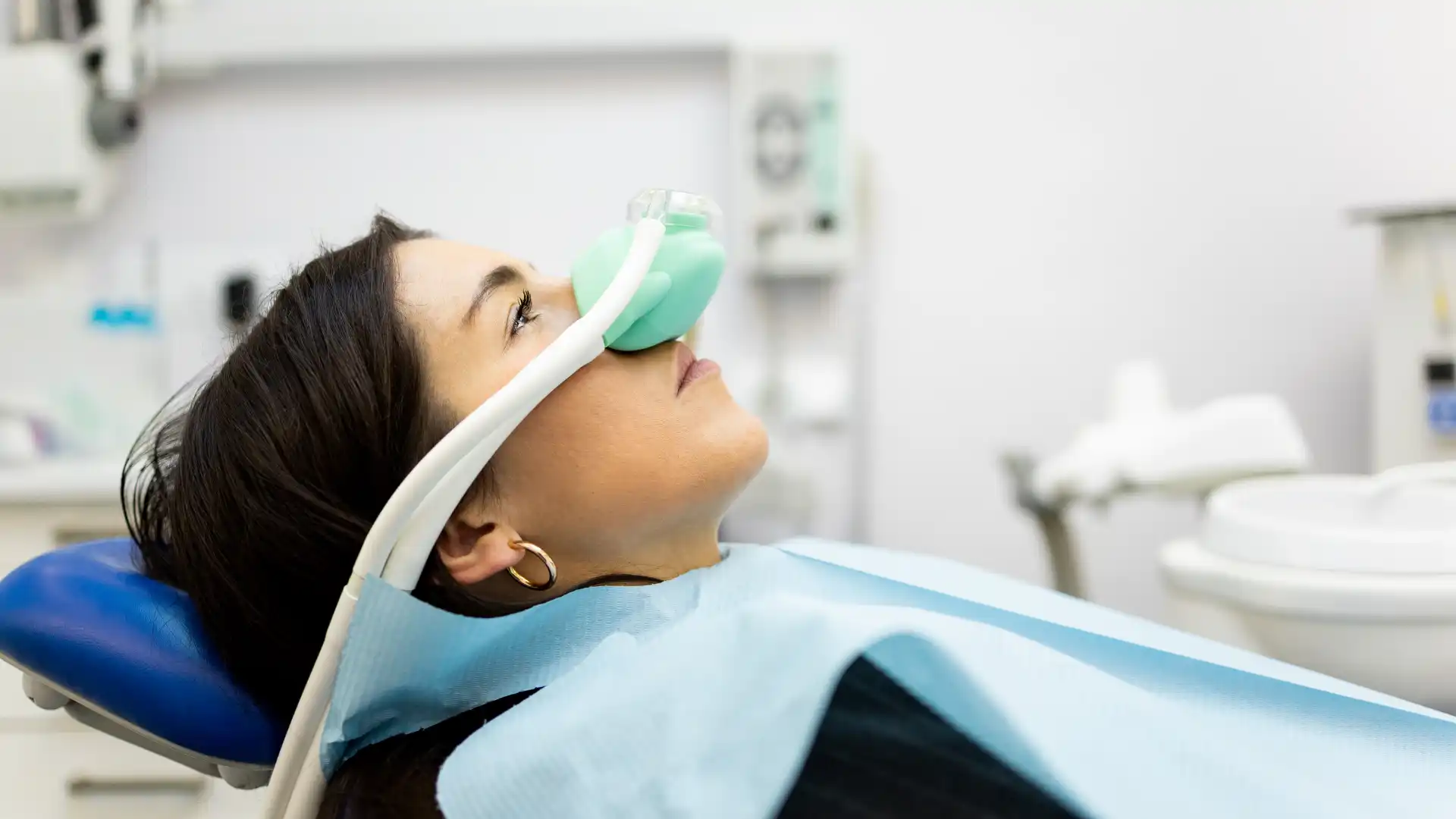 Patient receiving nitrous oxide sedation through a nasal mask at a dental clinic