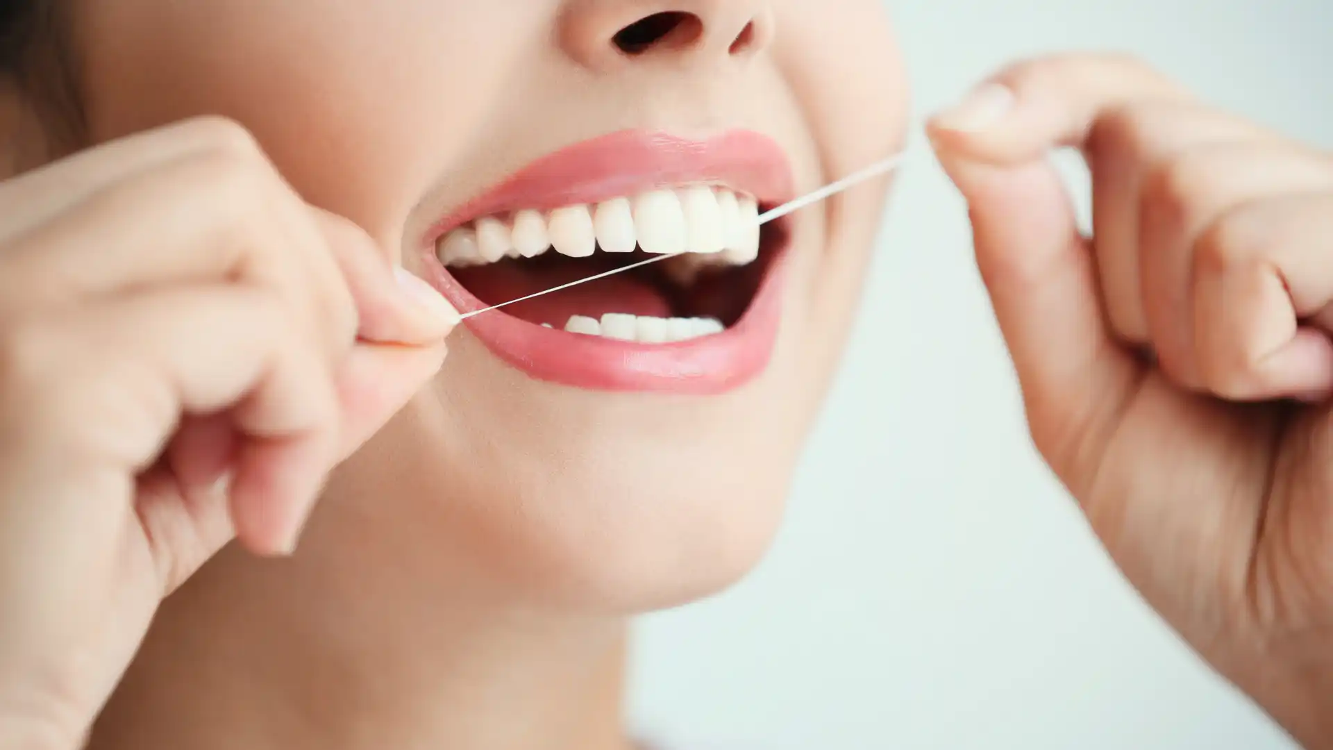 Person flossing teeth with dental floss.