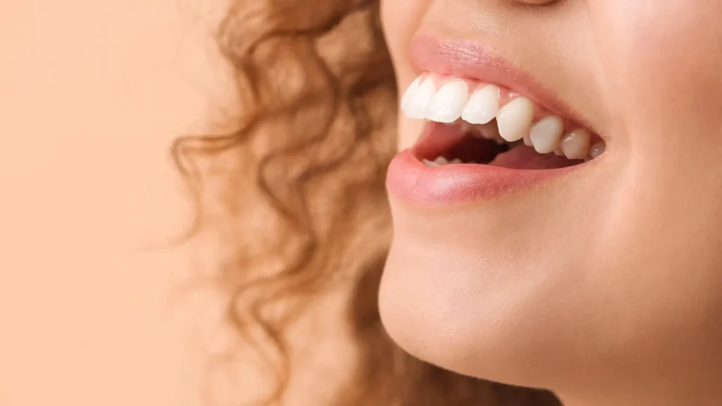 Close-up of a smiling woman with curly hair and white teeth.