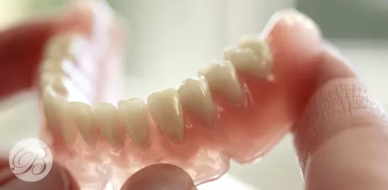  A person holding a dental implant alongside a natural tooth, showcasing dental restoration options.