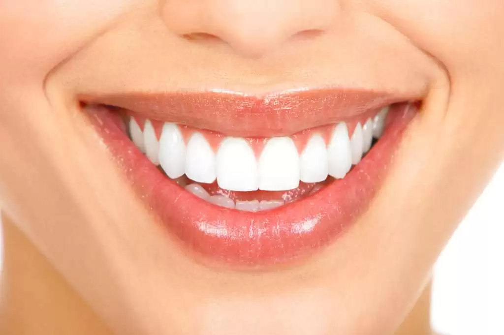 A woman with a bright smile, showcasing her white teeth, exudes warmth and happiness.