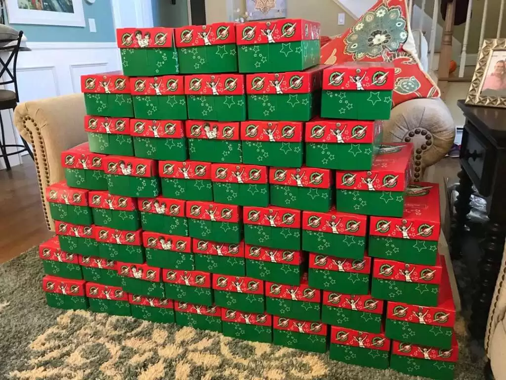 A large stack of red and green gift boxes arranged in a pyramid shape inside a living room.