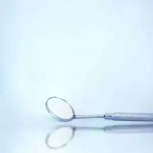 A metal spoon resting on a smooth blue surface, showcasing its reflective surface and sleek design.