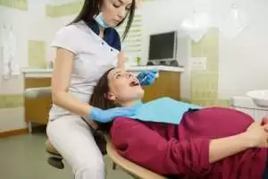 A woman receiving a dental cleaning from her dentist in a clinical setting