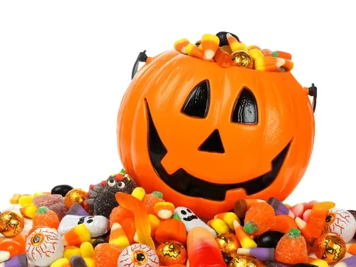 A pumpkin candy bucket overflowing with Halloween treats.