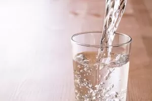 A glass of water is being poured into another glass, capturing the flow and clarity of the liquid.