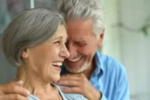 An older couple joyfully smiles and laughs together, showcasing their deep bond and happiness.