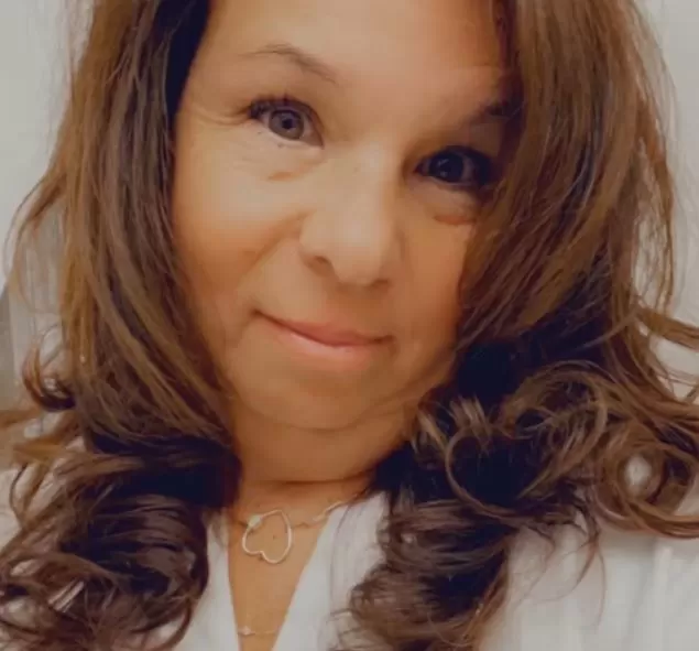 A woman with curled hair smiles subtly at the camera.